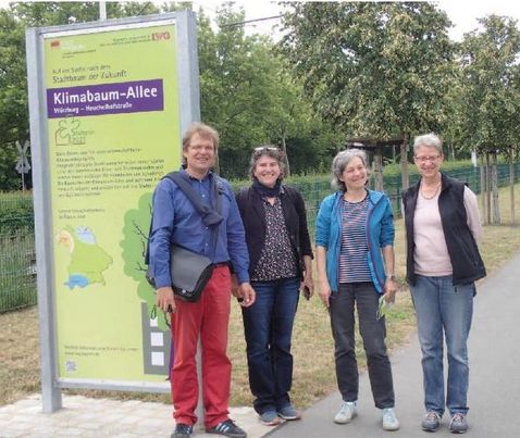 Vier Personen (Dr. Susanne Böll von TP5 und Dr. Sandra Gloor vom SWILD sowie Mitarbeiter) vor einem Informationsschild der Klimabaum-Allee